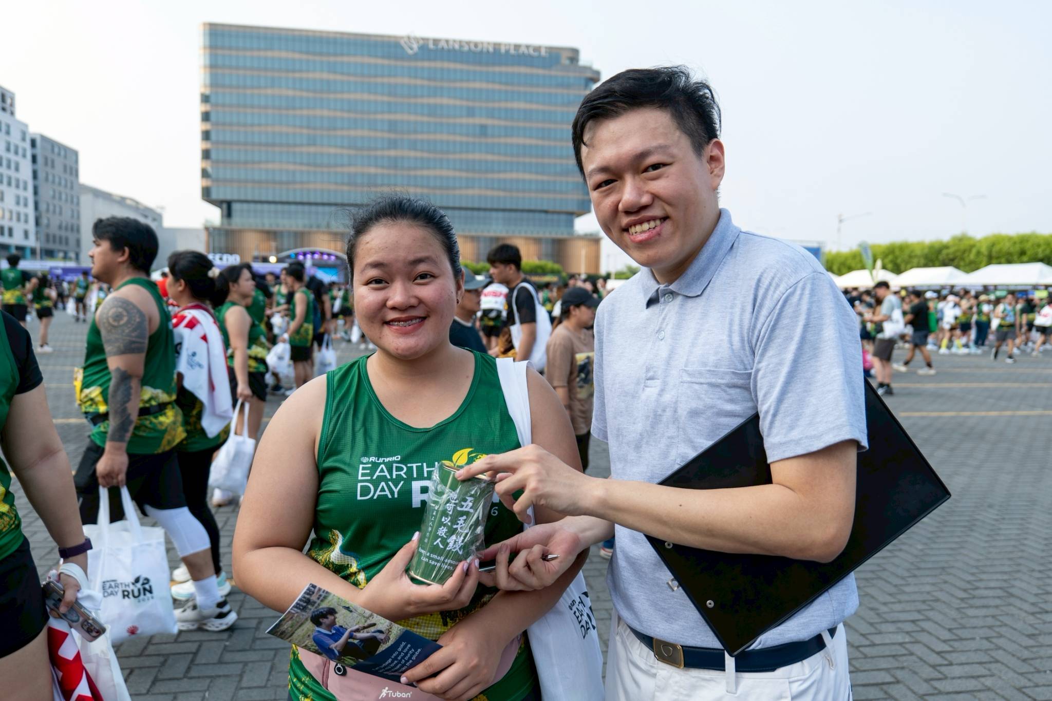 A runner receives a coin bank from Tzu Chi Partnerships Officer Clifford Co. 