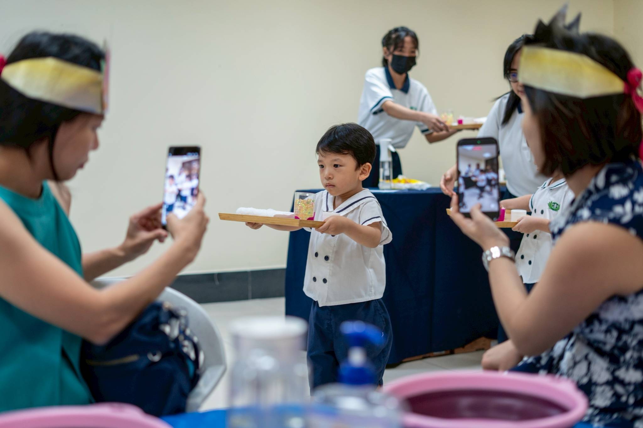 Out of love for their moms, nursery students carried trays with spa sets, moving carefully in small steps to ensure safe delivery to the tables.