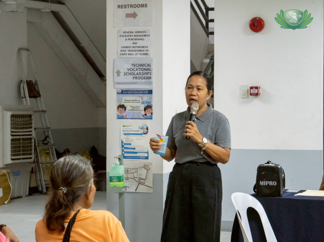 While waiting to receive a hearing aid, patients listen to Tzu Chi volunteer Julie Collado give a brief history of Tzu Chi and its founder, Buddhist nun Dharma Master Cheng Yen.  