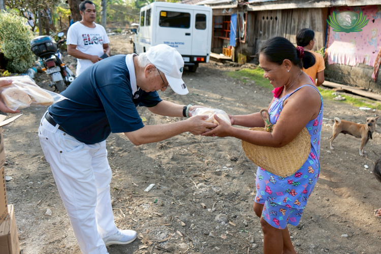 Tzu Chi volunteer James Cheng bows as he offers a resident of Barangay Dikapanikian bread during an ocular survey. 