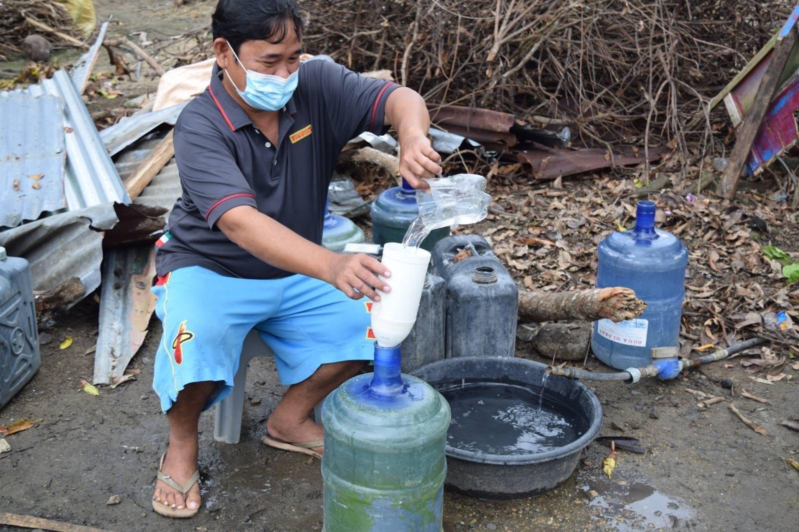 A man collects potable water from a hose. Clean drinking water has been hard to come by since Super Typhoon Odette disrupted lives last December. 
