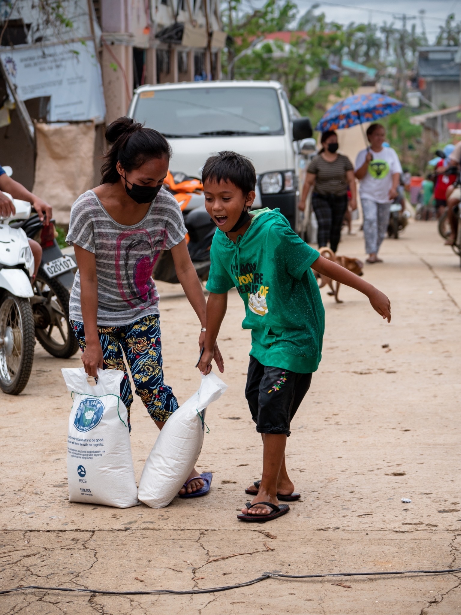 In CPG, a boy excitedly assists his mother in carrying their rice relief. 【Photo by Michael Sanchez】