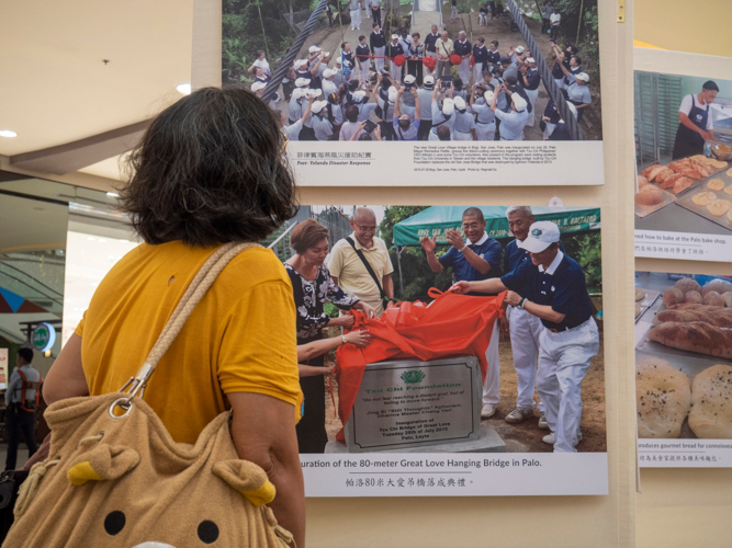 Shoppers stop to look at the pictures, recalling perhaps their own painful memories of the Category 5 storm.  【Photo by Matt Serrano】