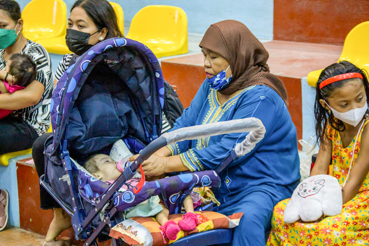 Meriam Zacaria Sangki, grandmother of Raihan, gives Raihan milk while waiting to be seen by the doctors. 【Photo by Marella Saldonido】