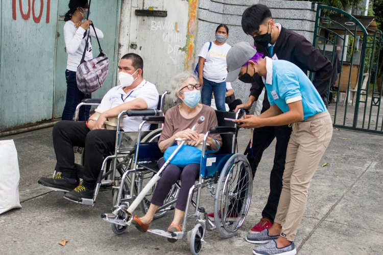 Tzu Chi scholars assist a beneficiary in a wheelchair.