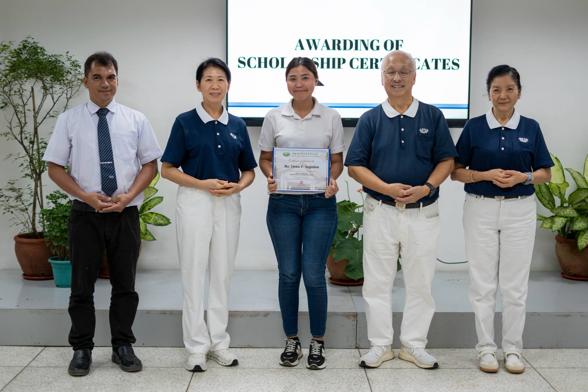 Shielded Metal Arc Welding scholar, Ma. Elena Soguilon (center) proudly holds her scholarship certificate alongside Tzu Chi volunteers.
