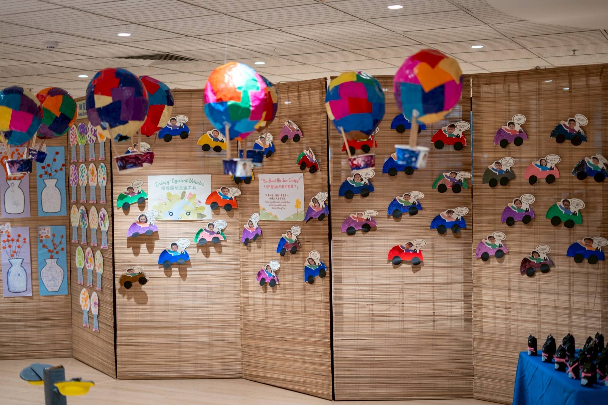 Nursery students affixed photos of their faces on paper sculptures of submarines, cars, planes, and hot air balloons.