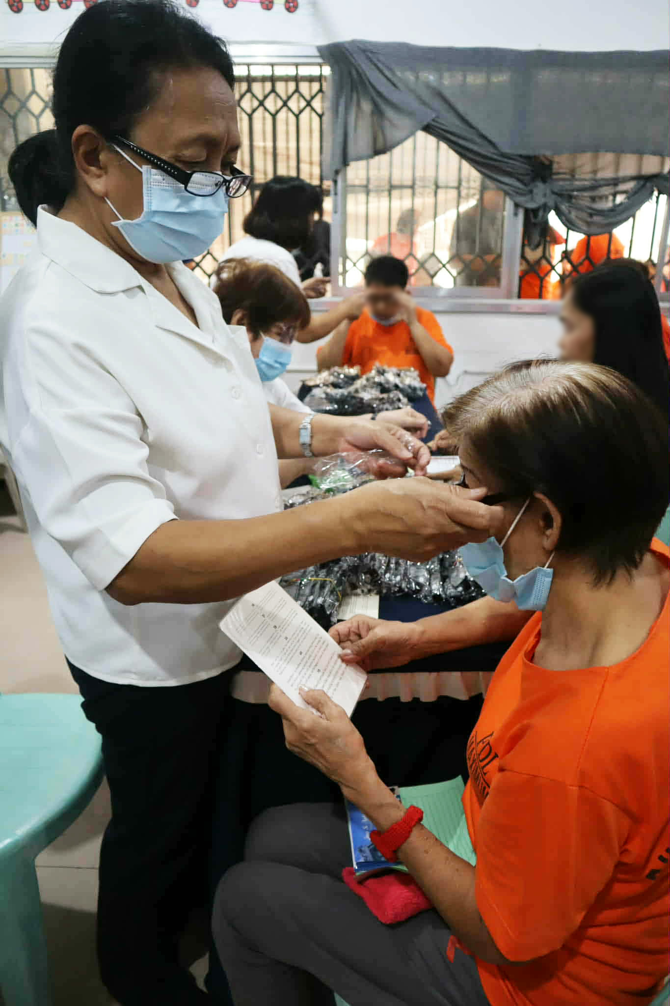 A doctor helps a PDL patient find the right pair of reading glasses. 