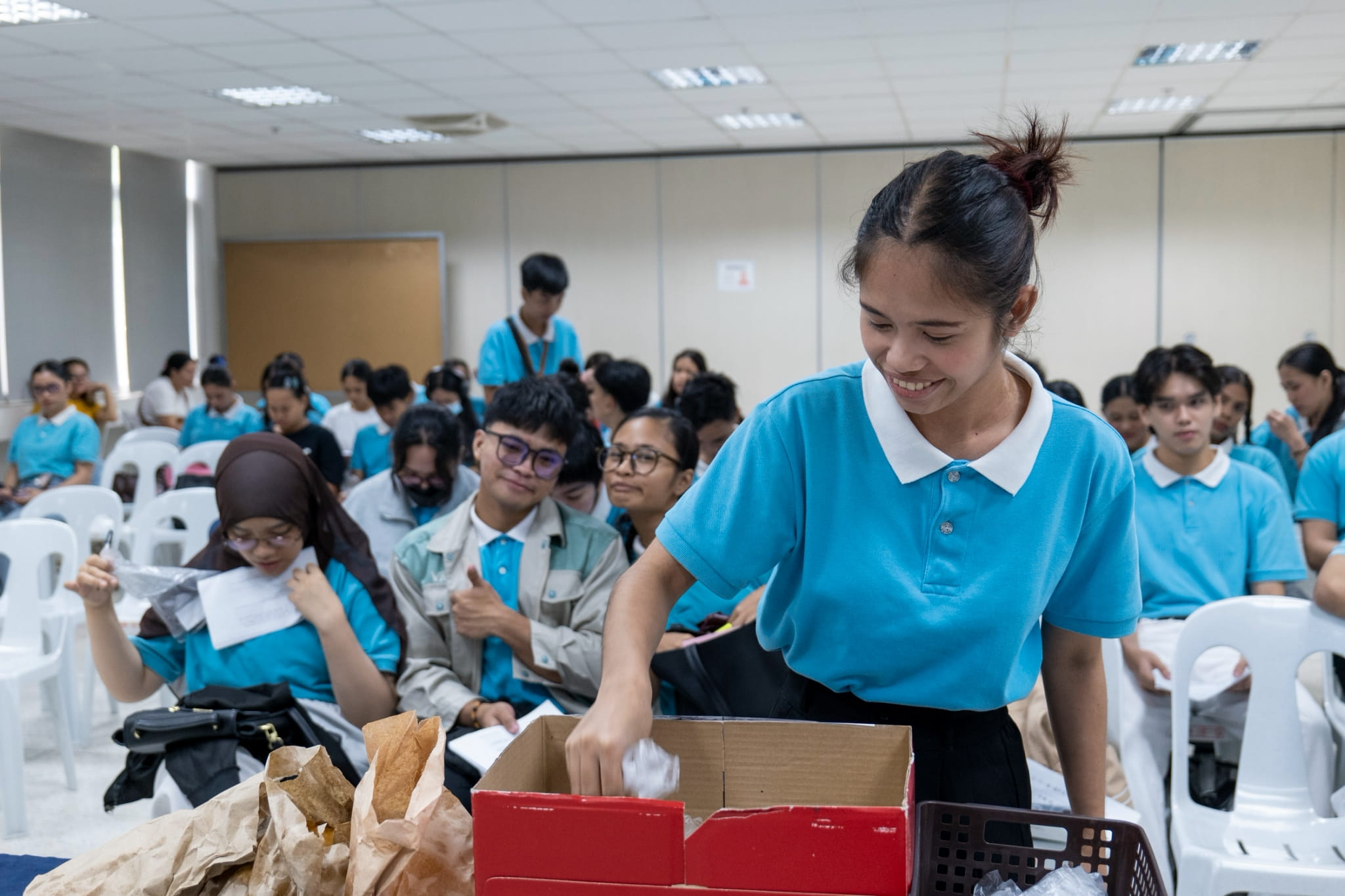 While waiting for their exit interviews, scholars at a holding area drop their pledges for Davao Occidental earthquake victims in a donation box. 