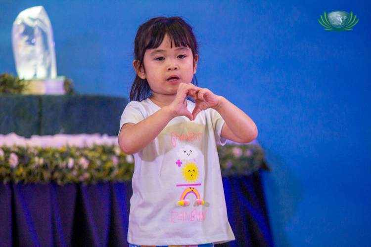 A student gives a cute heart gesture to the audience.