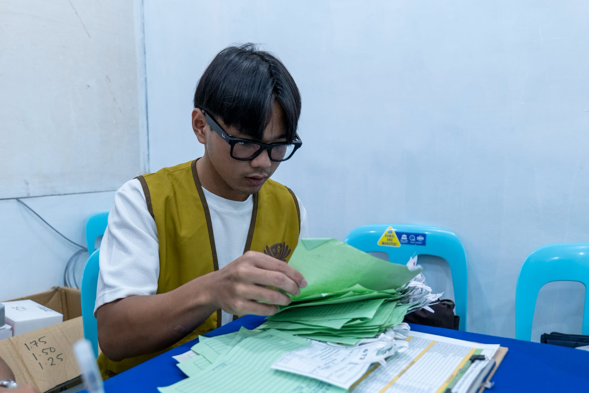 Gio Pamintuan counts and organizes the medical forms completed by patients after their eye checkups.