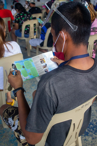 A beneficiary goes over a leaflet about the Tzu Chi Foundation. 【Photo by Matt Serrano】