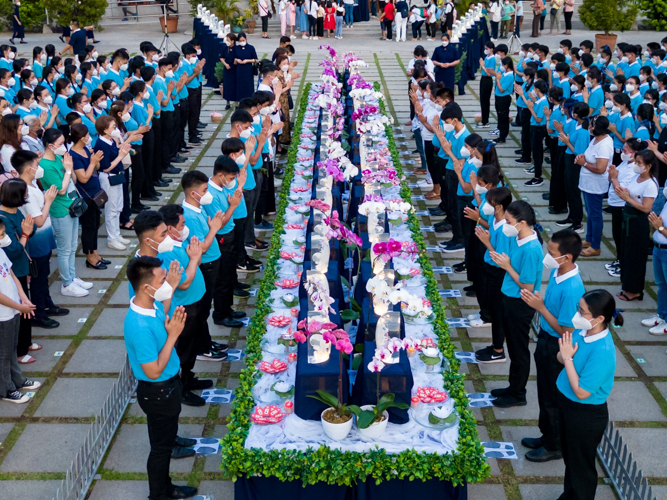 Tzu Chi scholars join their palms in prayer as they stand before a long table lined with crystal Buddhas. 【Photo by Daniel Lazar】