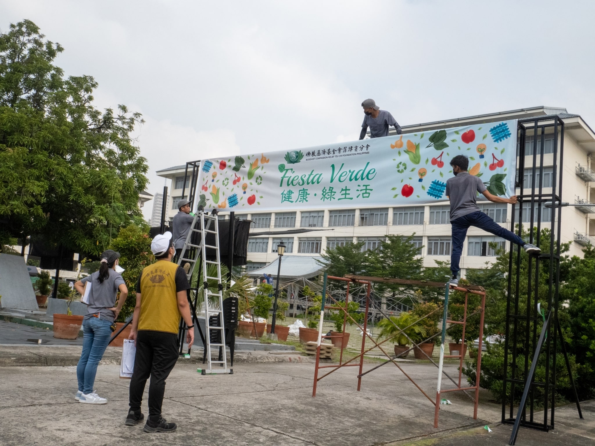 Volunteers hang the Fiesta Verde ’22 tarpaulin at the BTCC grounds.【Photo by Jeaneal Dando】