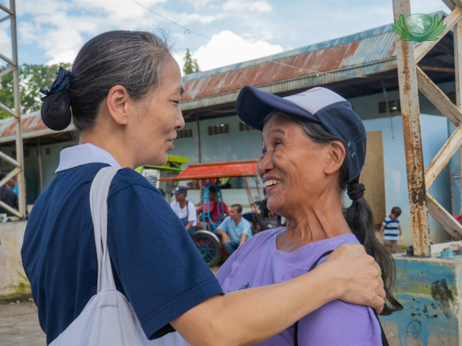 Tzu Chi volunteer Susie Weng Co comforts a resident from Bago City, encouraging her to stay positive in life.