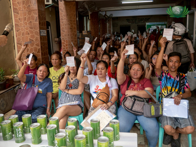 Beneficiaries raise their relief distribution stubs, saying “Thank you Tzu Chi, thank you Master Cheng Yen!”