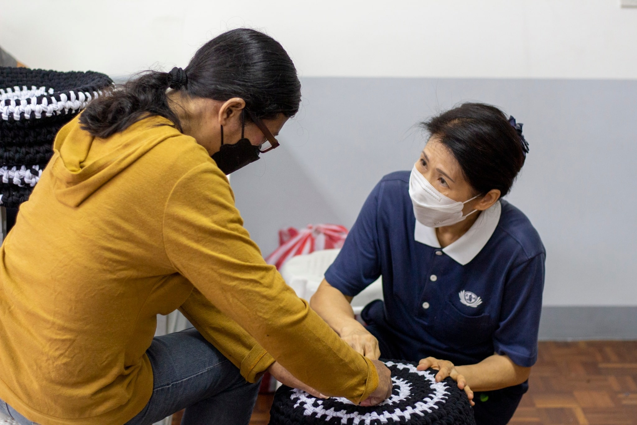 At Tzu Chi’s livelihood center, Marisol (in long sleeves to cover her skin lesions) discusses a stool seat with Tzu Chi Deputy CEO Woon Ng (right).【Photo by Harold Alzaga】