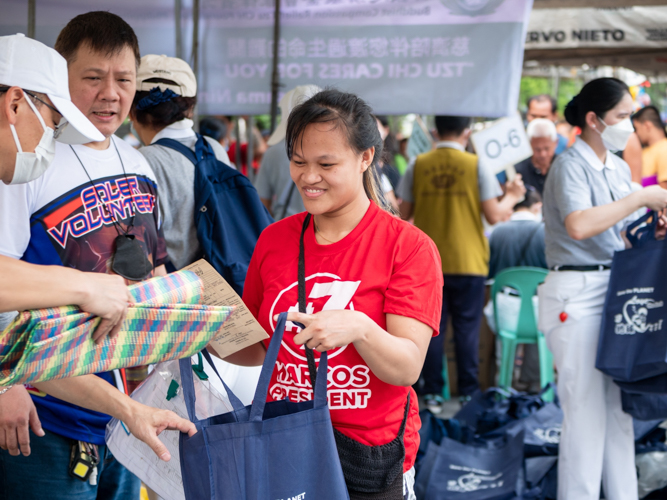 A beneficiary is all smiles as she receives a floor mat from a volunteer. 【Photo by Daniel Lazar】