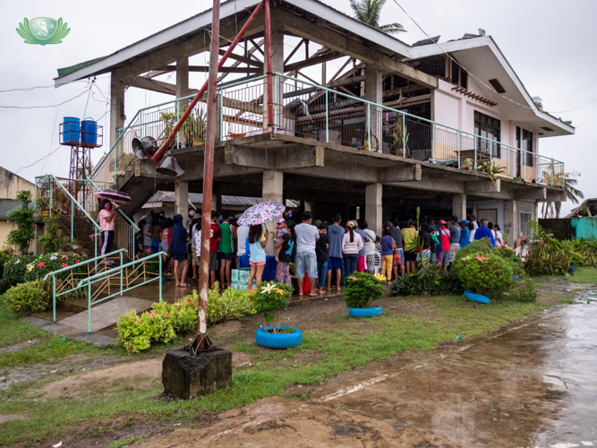 Barangay La Victoria residents line up outside a building whose roof had been blown away by Super Typhoon Odette.