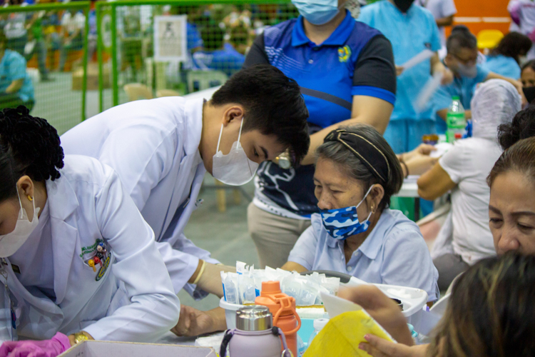 A MedTech student from Sultan Kudarat State University collects blood samples from a patient for her blood test. 【Photo by Marella Saldonido】