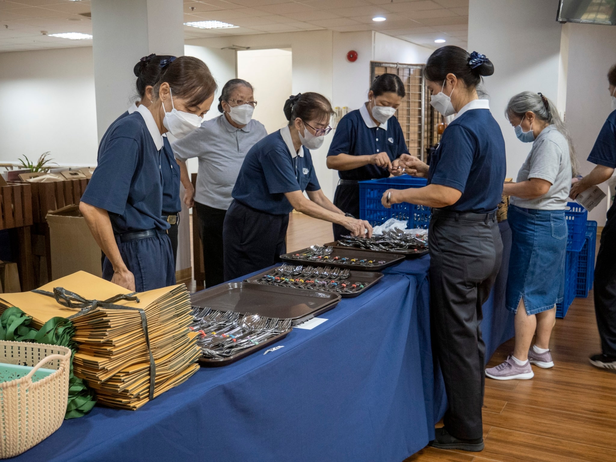 Volunteers lay out silverware. 【Photo by Matt Serrano】