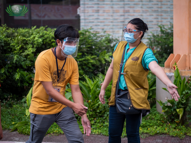 Student volunteer Catherine Jill Cilla (right) guides a tricycle driver beneficiary during a rice and relief goods distribution. 【Photo by Daniel Lazar】
