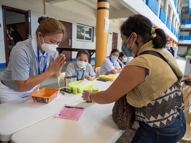 A volunteer bows after she dispenses a beneficiary’s prescribed medicines. 【Photo by Matt Serrano】