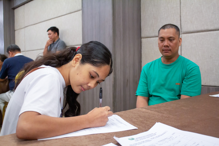 Daniella Diane Simran signs forms for her Tzu Chi scholarship as her uncle Joeward looks on. 【Photo by Marella Saldonido】