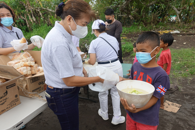 A boy from Bicol receives a large bowl of rice porridge from a Tzu Chi volunteer.