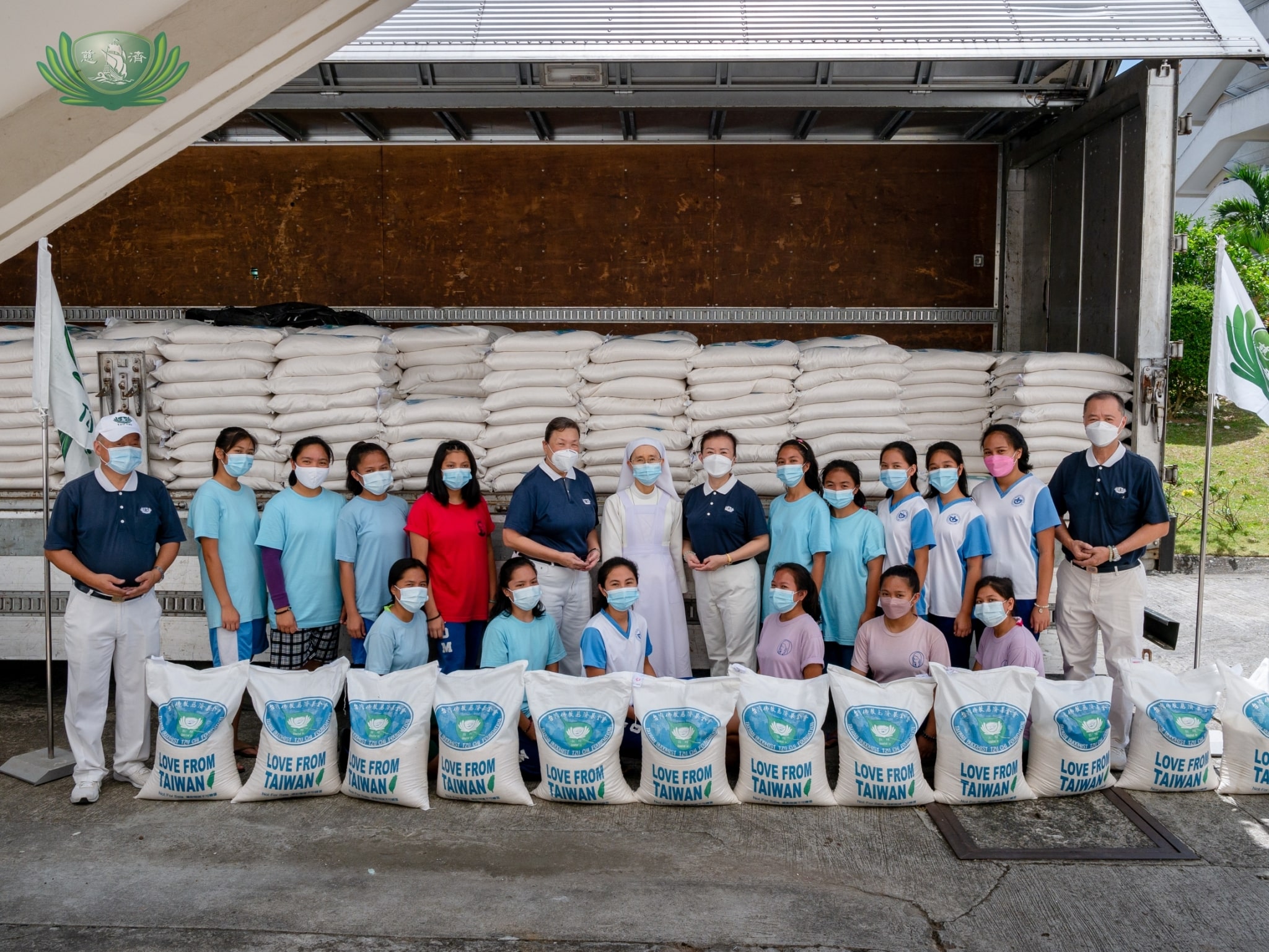 Sisters of Mary nuns and Girlstown students pose with Tzu Chi volunteers by the truck carrying donated sacks of rice.【Photo by Daniel Lazar】