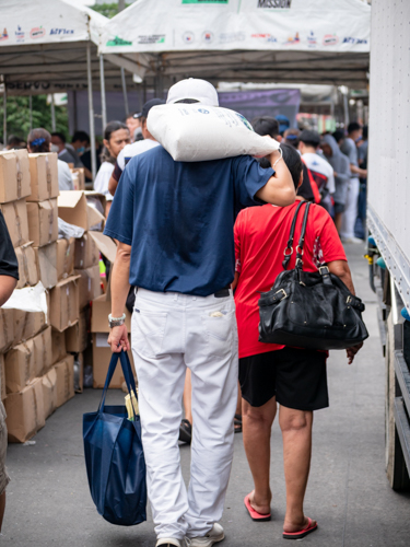 A volunteer helps a beneficiary take home a sack of 10kg rice and a bag of daily essentials. 【Photo by Daniel Lazar】