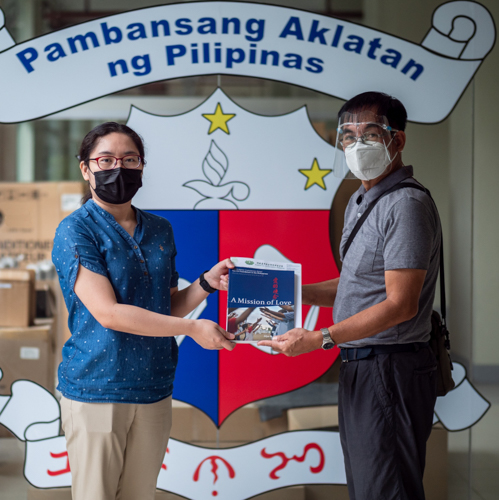 National Library of the Philippines librarian Melody Madrid (left) receives a copy of “A Mission of Love” from Tzu Chi volunteer Larry Velasquez. 【Photo by Daniel Lazar】