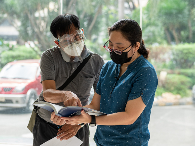 Tzu Chi volunteer Larry Velasquez (left) and National Library librarian Melody Madrid look through the pages of “A Mission of Love.”【Photo by Daniel Lazar】