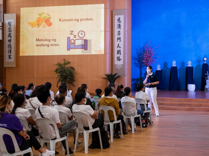 Volunteer Jane Sy enumerates the good deeds beneficiaries can try in their Tzu Chi “bingo cards.” 【Photo by Daniel Lazar】