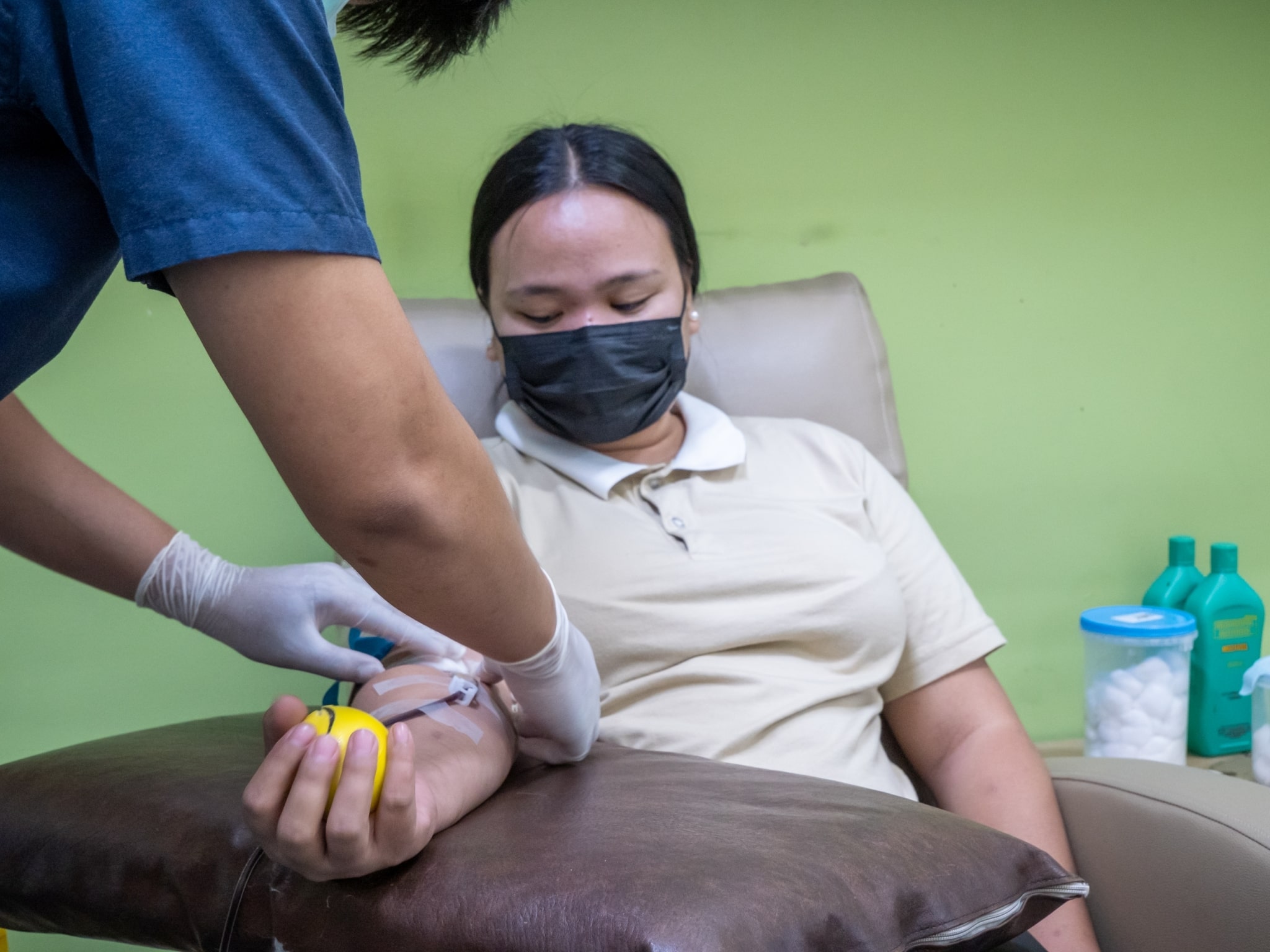 Tzu Chi caregiver scholar Lerma Villocillo watches a phlebotomist as he readies her for blood donation.【Photo by Marella Saldonido】