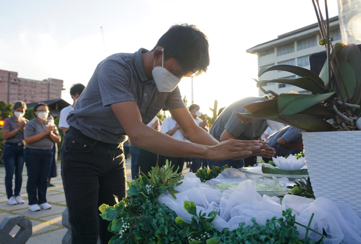 A volunteer bows before a crystal Buddha and touches a bowl of water. The gesture is akin to touching the feet of Buddha. 【Photo by Jenie Sy Lao】