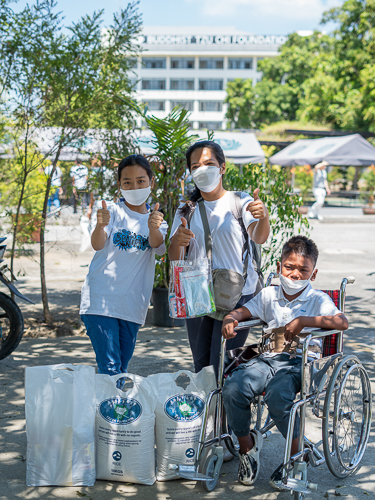 Homemaker Lenlen Galban (center) makes the heart sign together with her daughter, 13-year-old Princess (left) and 11-year-old Tzu Chi beneficiary Prince, after they claim their 20kg rice, personal hygiene kit, and bag of groceries. 【Photo by Marella Saldonido】