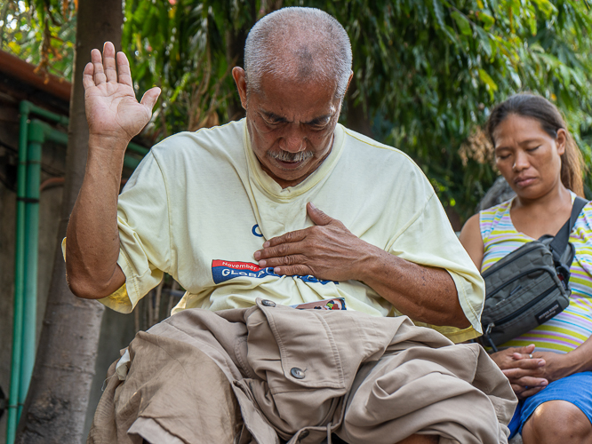 A beneficiary of the fire relief wholeheartedly participates in prayer. 【Photo by Marella Saldonido】
