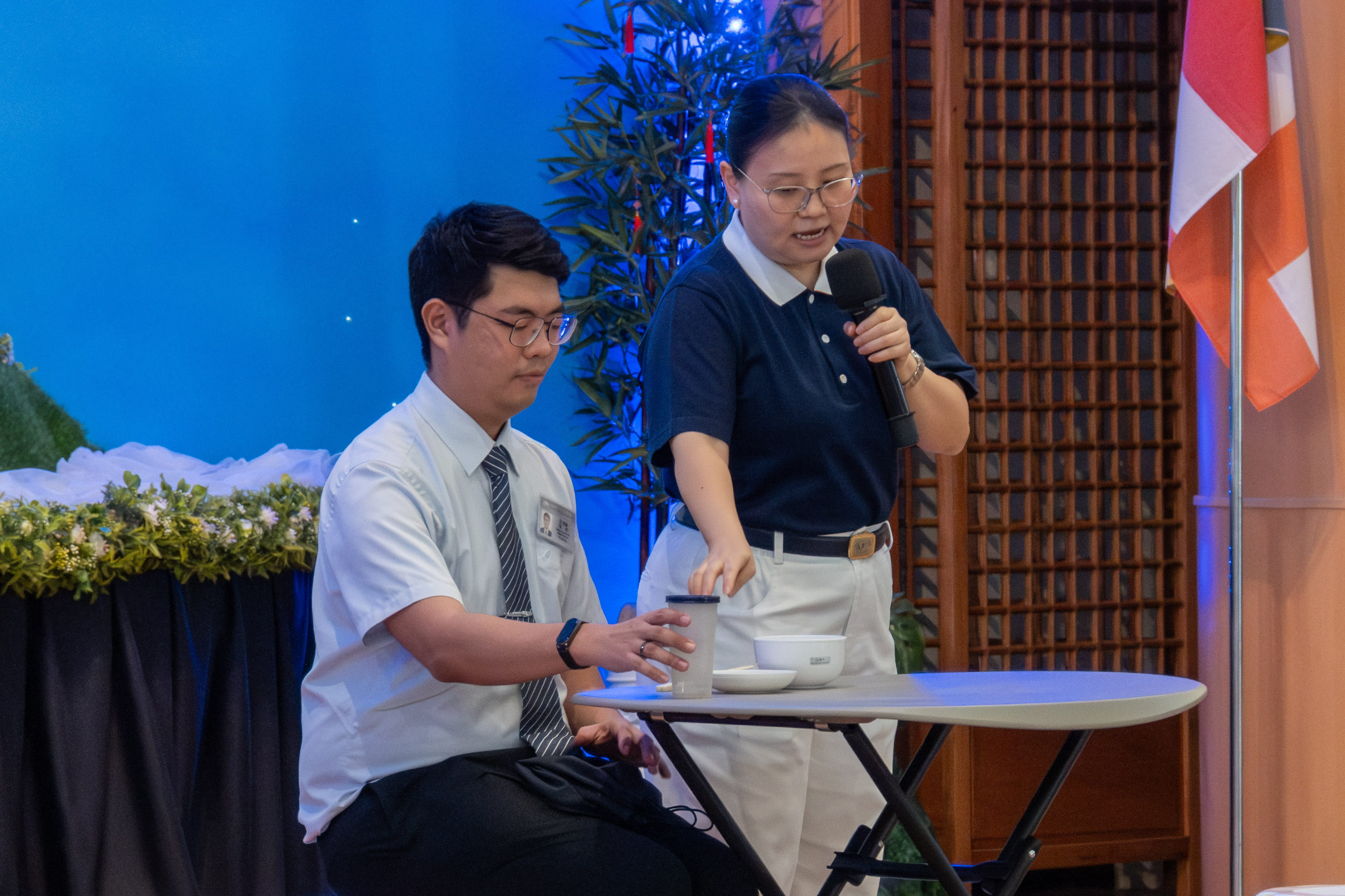 Tzu Chi volunteers Mayee Lee (standing) and Kinlon Fan demonstrate Tzu Chi style dining.