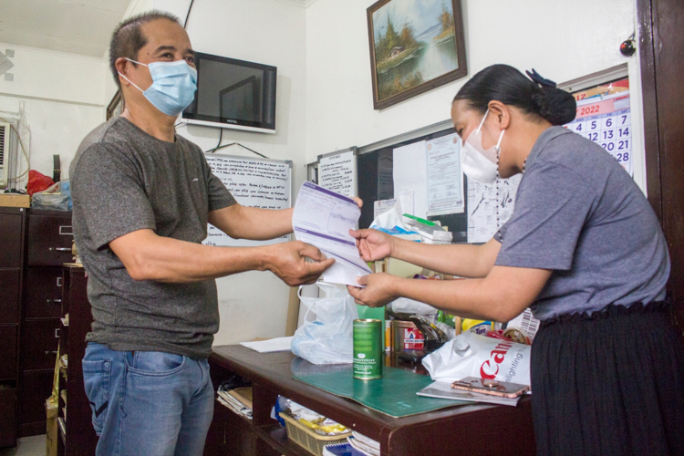 Virgilio Rom gives a deposit slip of his donation to Tzu Chi staff—his third since returning to work three months after his successful angioplasty operation. “I promised myself to give back to Tzu Chi in any way that I can, so I can also help others,” he says. 【Photo by Matt Serrano】