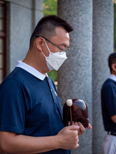 A volunteer strikes a bell to signal participants to walk and bow.【Photo by Daniel Lazar】