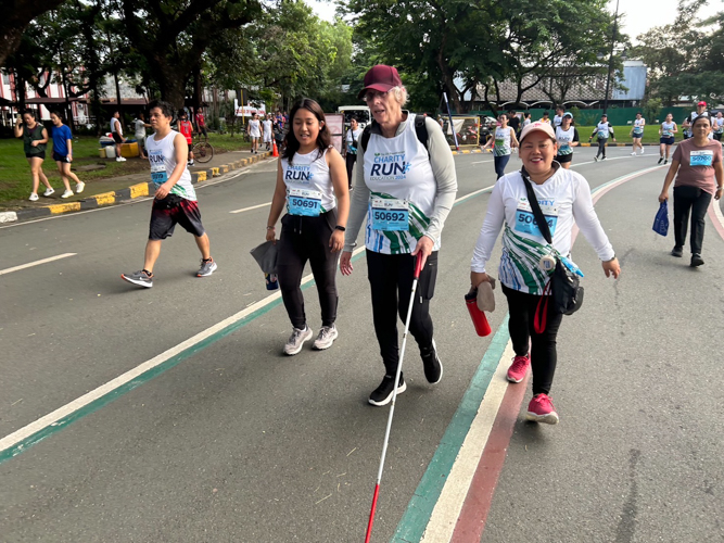 A blind participant uses a cane and the company of friends to cover 5K.