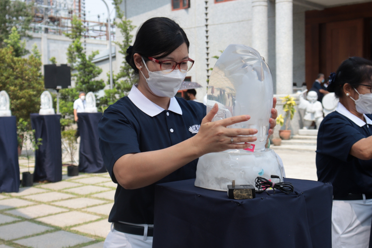A volunteer positions a crystal Buddha on a stand. For this 3-in-1 event, 168 crystal Buddhas were used. 【Photo by Kinlon Fan】