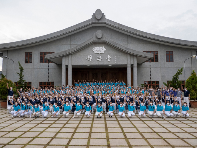 Tzu Chi Youth Camp scholars and volunteers pose for a photo before the Jing Si Auditorium.【Photo by Matt Serrano】