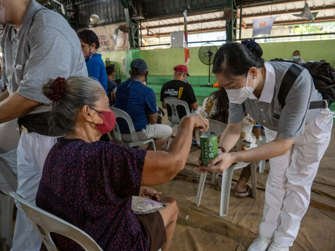 Touched by the volunteers’ kindness, Elizabeth donates some of her money to the Tzu Chi coin bank. 【Photo by Jeaneal Dando】