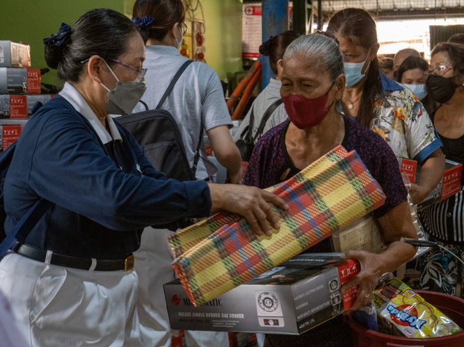 Elizabeth, who earns Php 100 for a day’s work of peeling a sack of garlic in the market, receives a sleeping mat, among other relief items to help her restart her life. 【Photo by Jeaneal Dando】