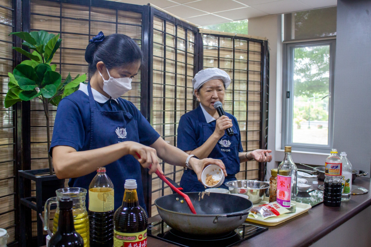Volunteer Sally Yuñez (right) explains the cooking process of a plant-based dish. 【Photo by Marella Saldonido】