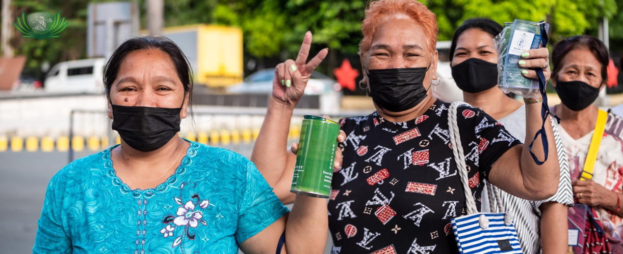 Beneficiaries wave their coin banks while waiting to claim their rice and groceries. 【Photo by Daniel Lazar】