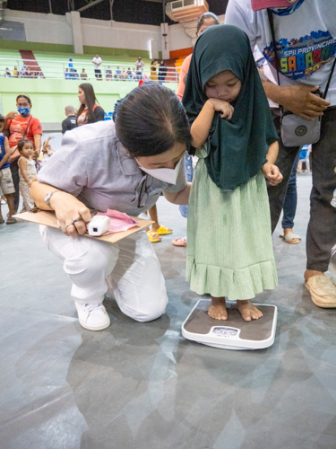 Tzu Chi volunteers help patients get their weight.【Photo by Matt Serrano】