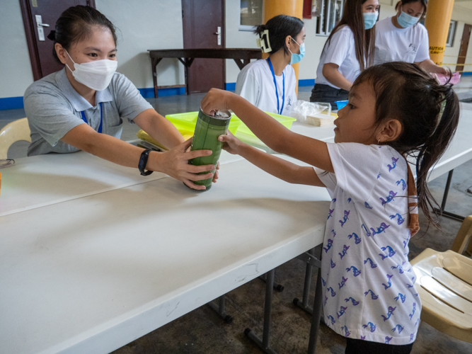 Proof that no one is too young or old to help, a child puts a pledge in a Tzu Chi coin can. 【Photo by Matt Serrano】